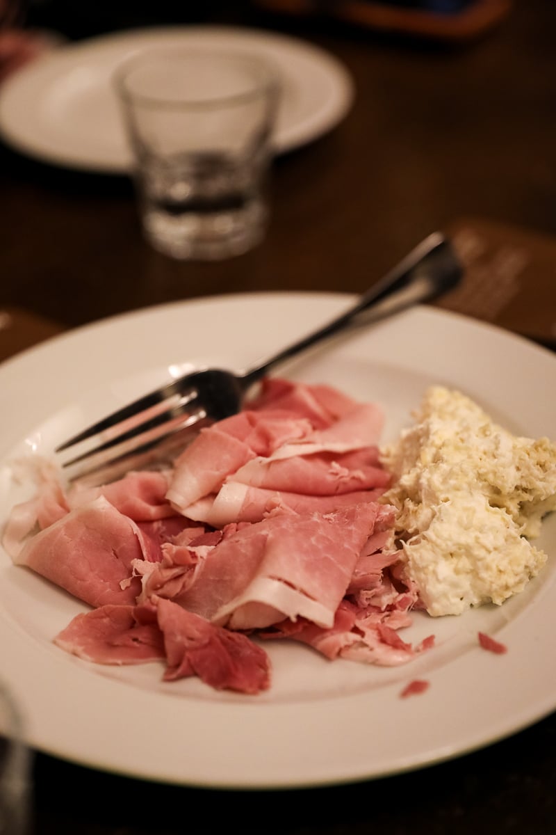 Plate of thinly sliced Prague ham served with a generous portion of whipped horseradish.