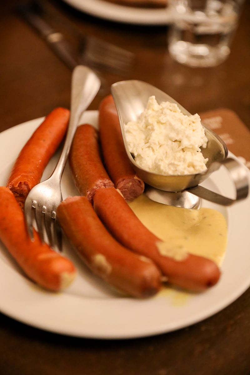 Plate of Czech sausages with spicy mustard and a scoop of creamy horseradish sauce.