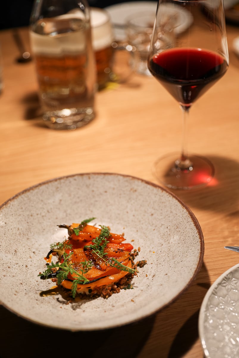 Modern Czech dish of blackened peppers with creamy Gran Moravia cheese dip, served with a glass of red wine.