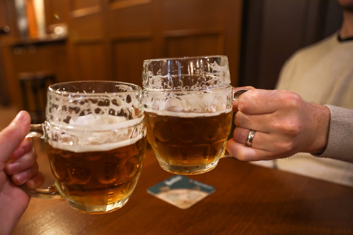 Clinking mugs of Czech beer inside a traditional Prague pub during a beer tasting tour.