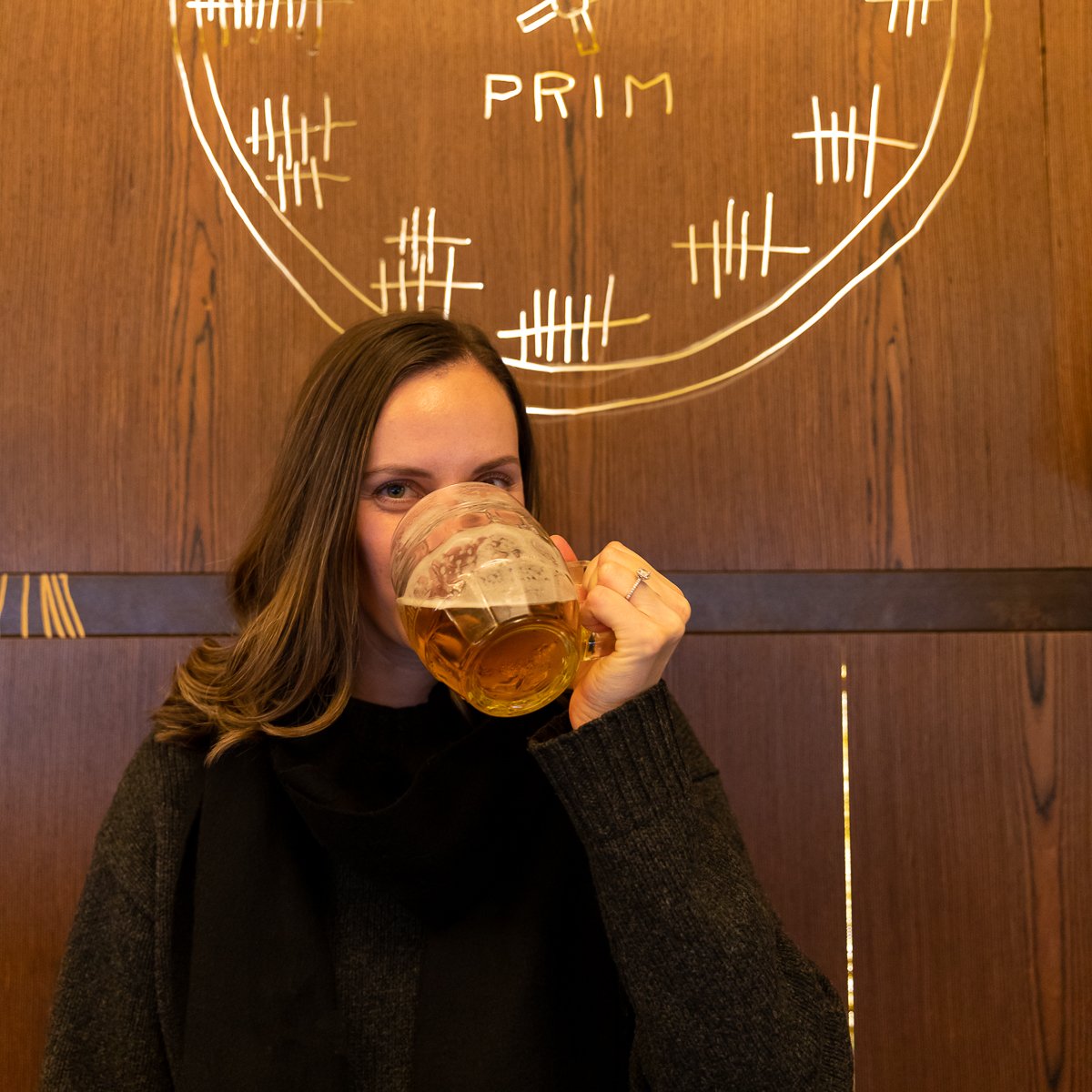 Maddy enjoying a pint of Czech beer during a Prague pub tour, seated inside a traditional beer hall.