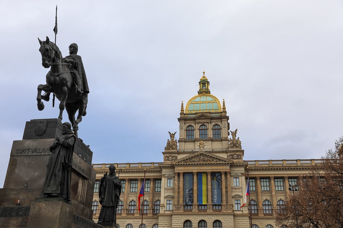 Statue of St. Wenceslas in front of the National Museum at Wenceslas Square in Prague, with the building’s golden dome and historic façade.