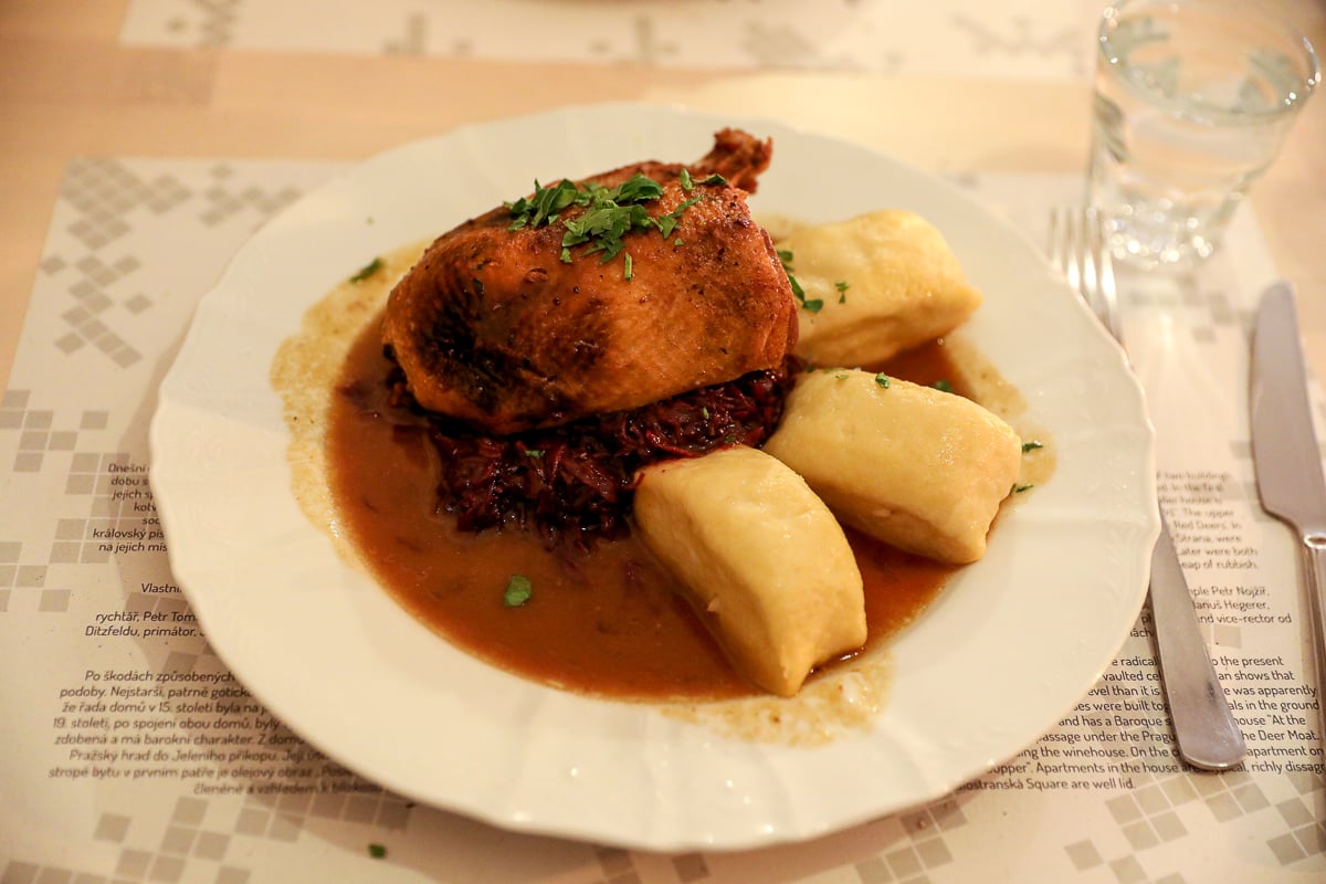 Czech meal of slow-roasted duck leg served with red cabbage, cranberries, and Bohemian potato dumplings at U Tří Jelínků restaurant in Prague.