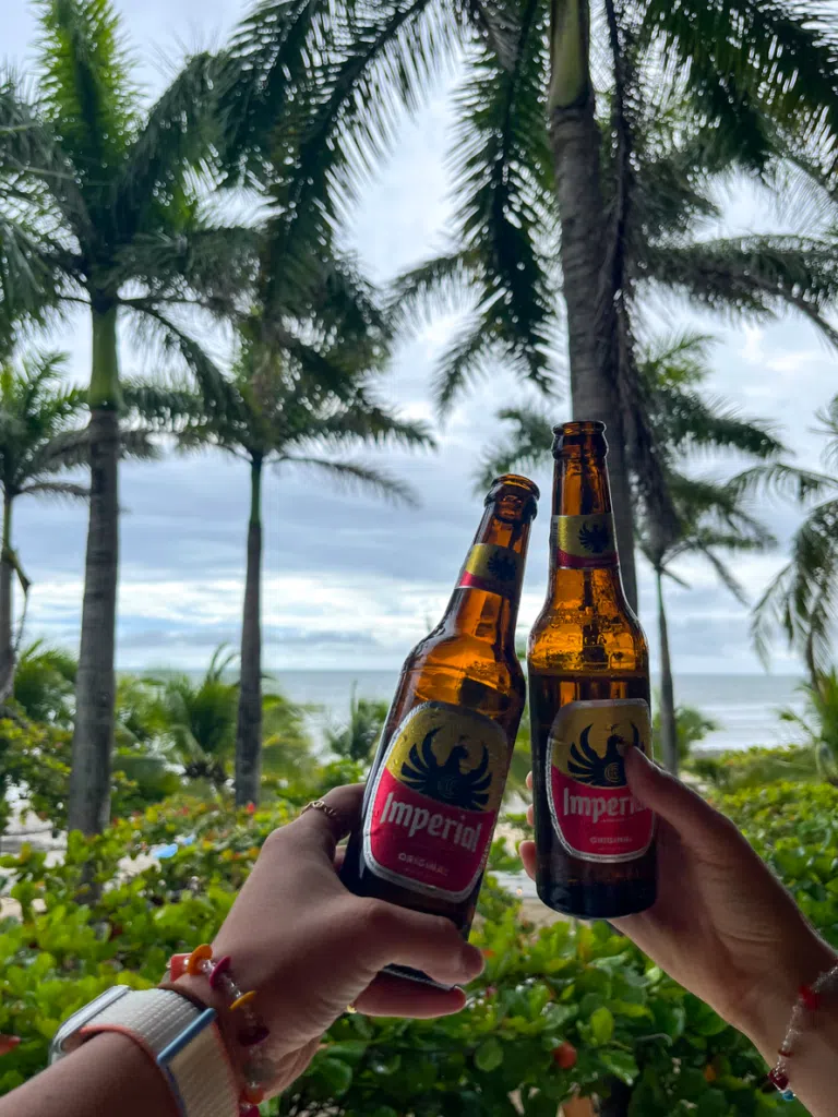 Holding up cold beer bottles while relaxing in Playa Negra