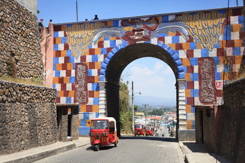 A unique archway in Chichicastenango with tuk tuks driving through