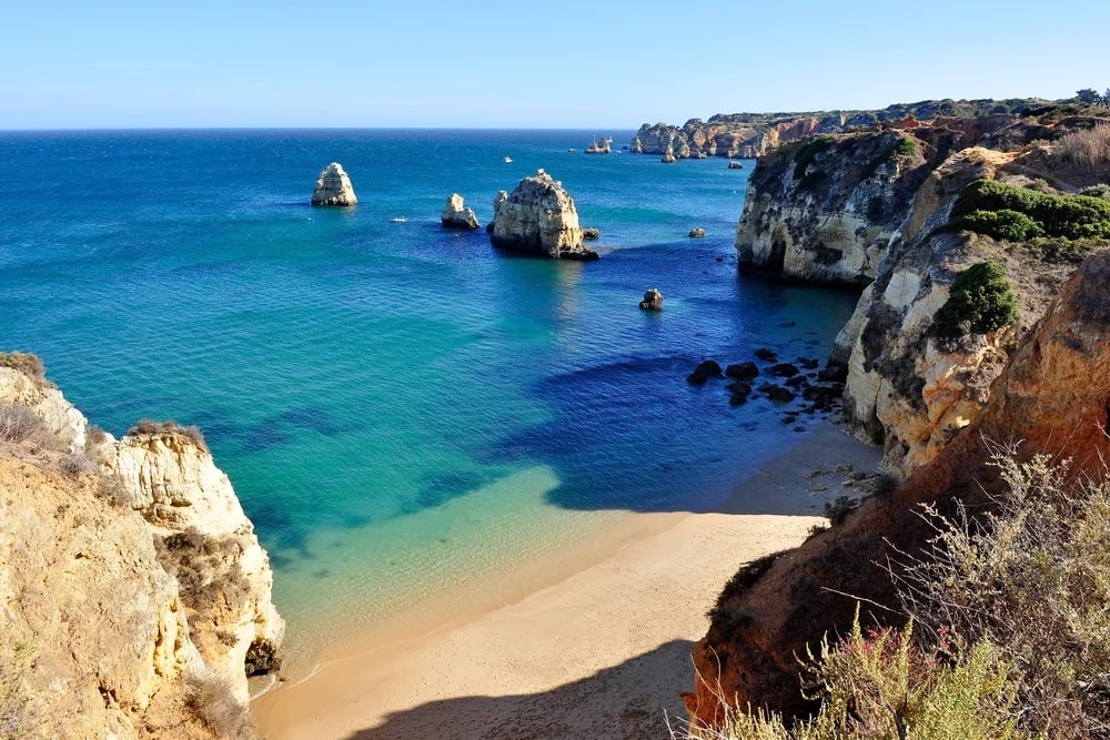 The Algarve Coastline with a sandy beach, rock formations, and steep cliffs.