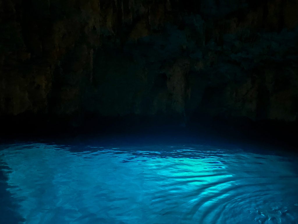 A dark view inside the Emerald Grotto near Positano, the water is glowing