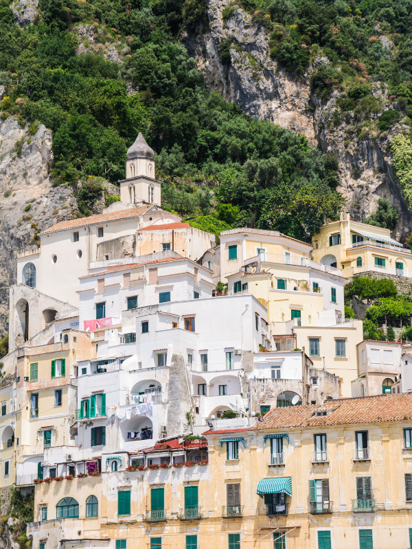 Old buildings stacked atop each other on a rocky and plant covered mountain in the Amalfi Coast