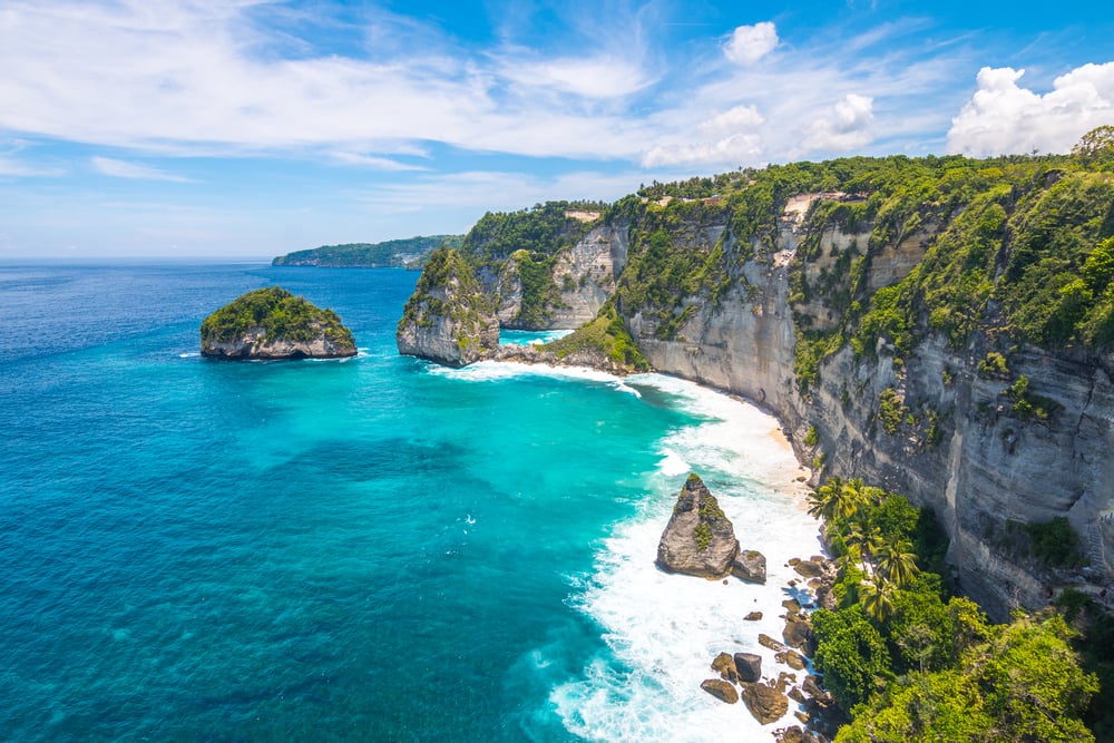 Gorgeous rocky coastline covered in greenery and surrounded by bright blue ocean