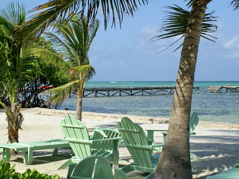 Wooden chairs on a white-sand beach in Ambergris Caye. This island should be included on all luxury Belize itineraries.