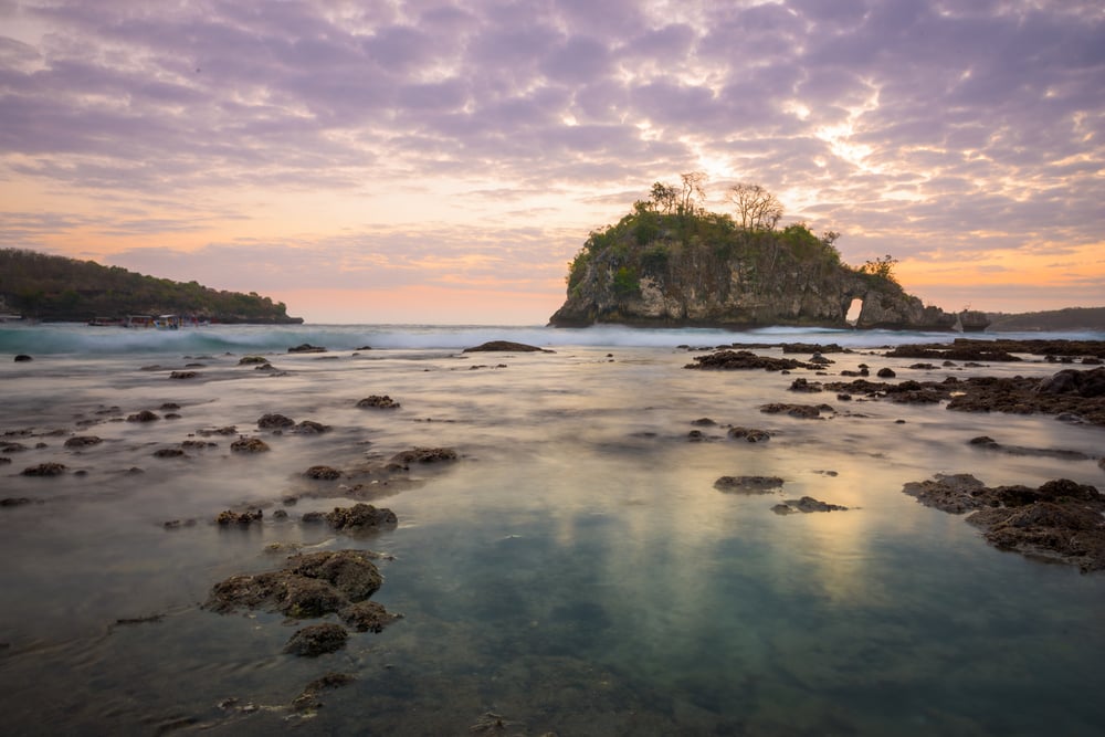Crystal Bay at low tide with the sunset behind the rock island on Nusa Penida, Bali
