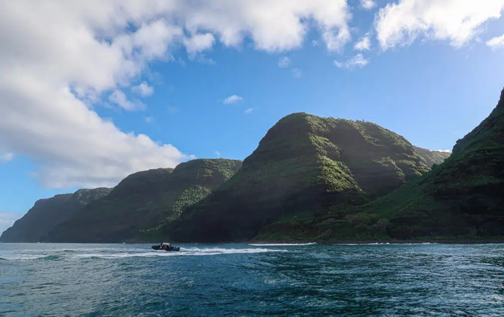 Raft adventure on Kauai's blue waters surrounded by green mountains. Book a raft tour when visiting Kauai.
