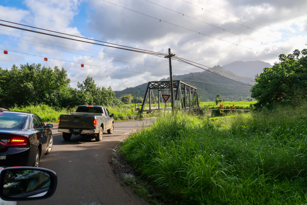 Vehicles passing through a bridge going to the island of Kauai during daytime.