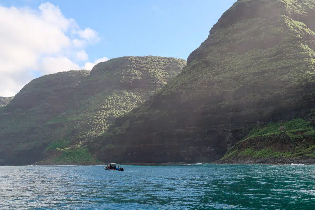 Group of people on a catamaran in Na Pali Coast. Booking these boat tours is a must-add in your Kauai vacation itinerary.