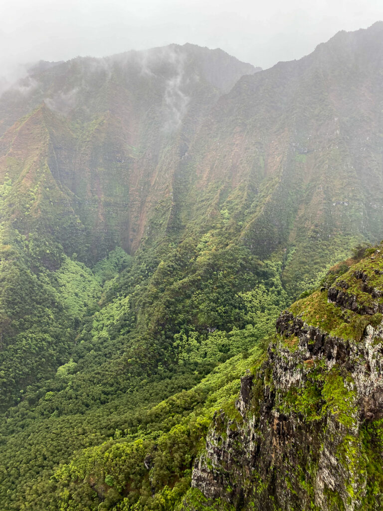 Mountains in Kauai covered in green forests with fog covering the higher peaks.