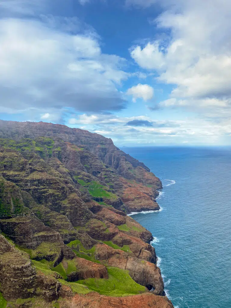 View of Kauai's mountains and beach from helicopter. A helicopter tour is a must for your Kauai vacation.