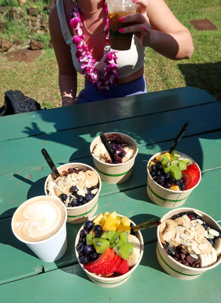 Healthy açai bowls, smoothie, and coffee on a wooden table at Little Fish Cafe. You won't be disappointed waiting in line for a breakfast when visiting Kauai.