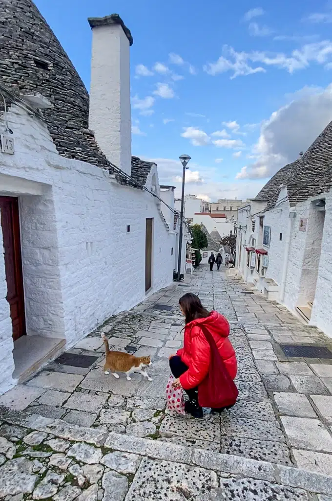 Melanie greeting a local cat in the street in Alberobello