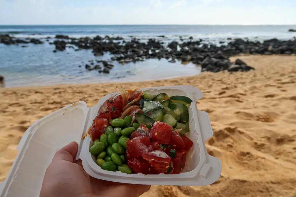 Holding a to-go serving of poké at Baby Beach. This fresh seafood is in almost every corner when you visit Kauai!
