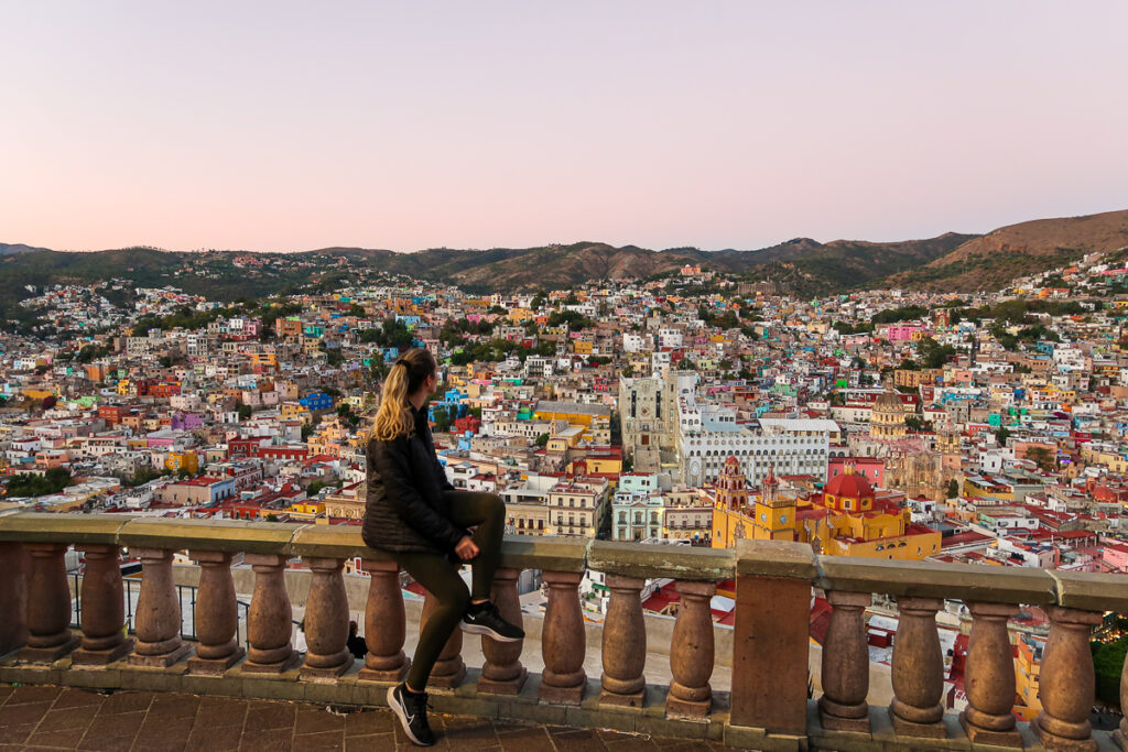 Maddy sitting on stone railings while admiring the colorful landscape of Guanajuato City. If you're looking for things to do in San Miguel de Allende, taking a day trip to Guanajuato is a must.