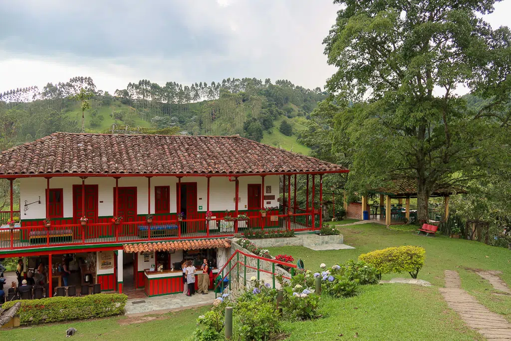 The El Ocaso Coffee Farm house with bright red doors and fences as tourists come over for a tour. The Finca El Ocaso's Coffee Tour is one of the most recommended things to do in Salento, Colombia especially if you're a certified coffee lover!