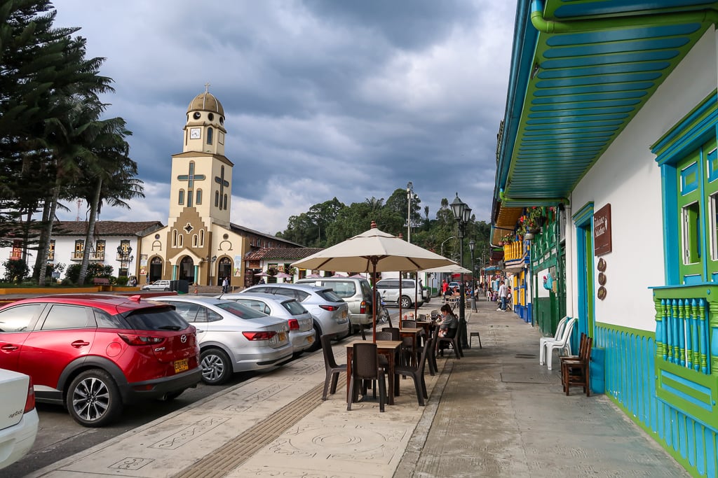 Cars parked in front of the outdoor dining tables in the Salento Main Square restaurants during daytime