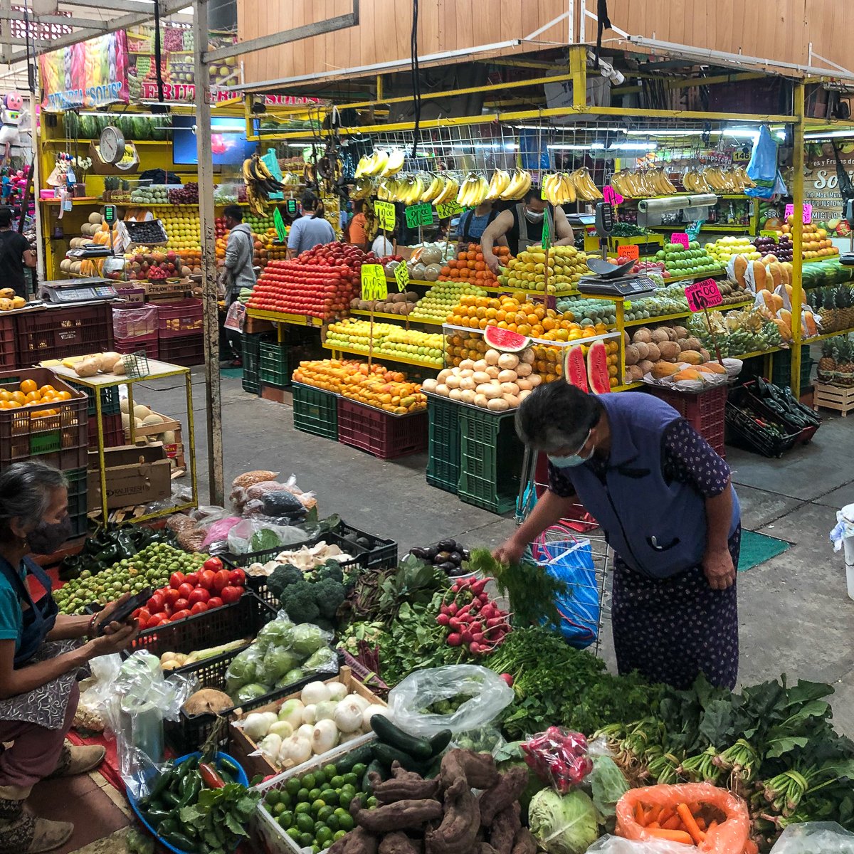 People shopping for vegetables and fruit in a colorful Mexican market