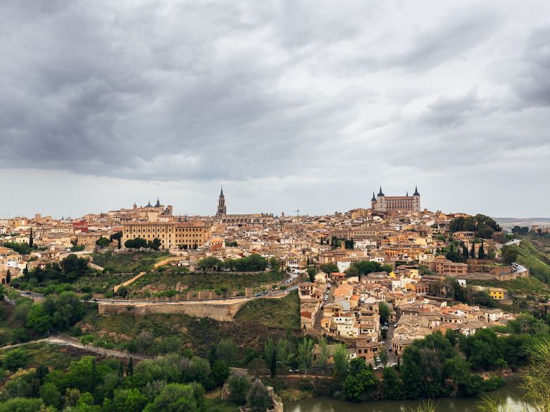 Panoramic view of historical buildings in Toledo, an old town in Spain, under cloudy skies. Witness every corner of this ancient city during your day trip to Toledo from Madrid.