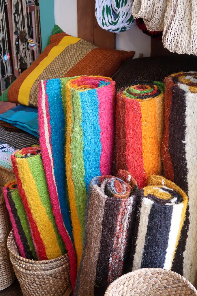 Beautiful colorful rugs stacked vertically inside woven baskets in a souvenir shop in Salento