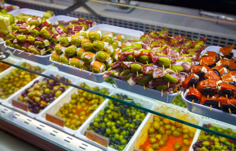 Fresh olives and other snacks on stall display in San Miguel Market to complete your one day in Madrid