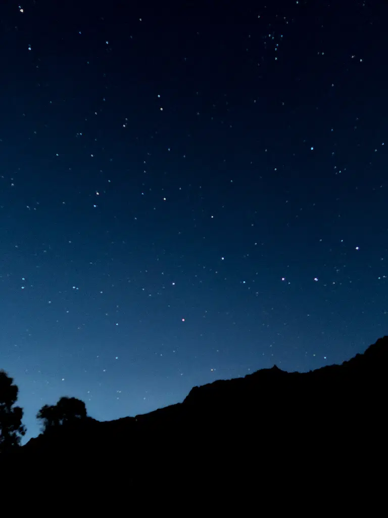 Beautiful night sky filled with bright stars and silhouettes of mountains and trees