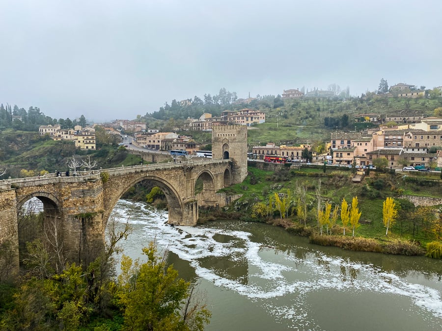 The grand monolithic bridge in Toledo with a river passing under its architectural arches. See Puente de Alcantara during your day trip to Toledo from Madrid.