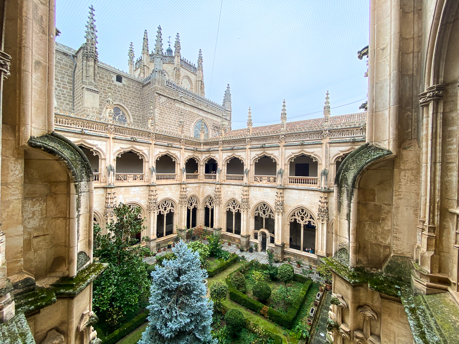 Beautiful cloister garden inside the Monastery of San Juan de los Reyes surrounded by Gothic hallways. This architectural masterpiece is a must-visit during your day trip to Toledo from Madrid.