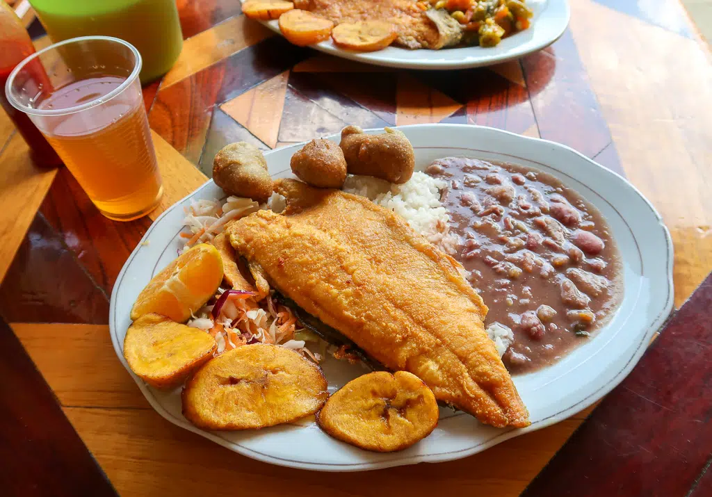 Tasty-looking fried trout with beans and rice on a white ceramic plate. If you're looking for the best food to eat in Salento, give this local specialty a try.