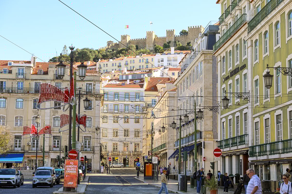 Tall, colorful buildings in Lisbon with a castle view atop a hill