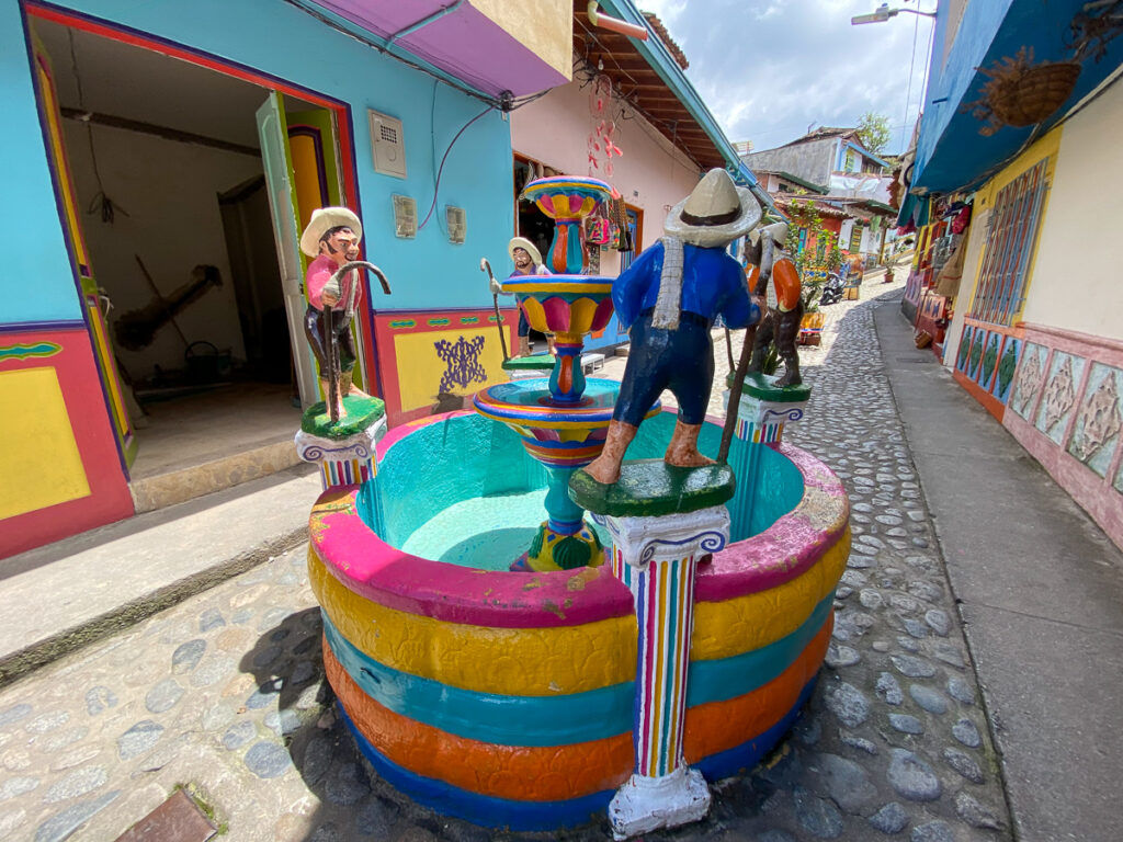 Colorful ceramic fountain in the middle of a cobblestone street in Guatape. In this guide, you'll find the best things to do in Guatape and many more.