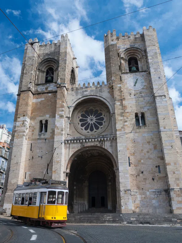 Yellow tram passing in front of Lisbon cathedral