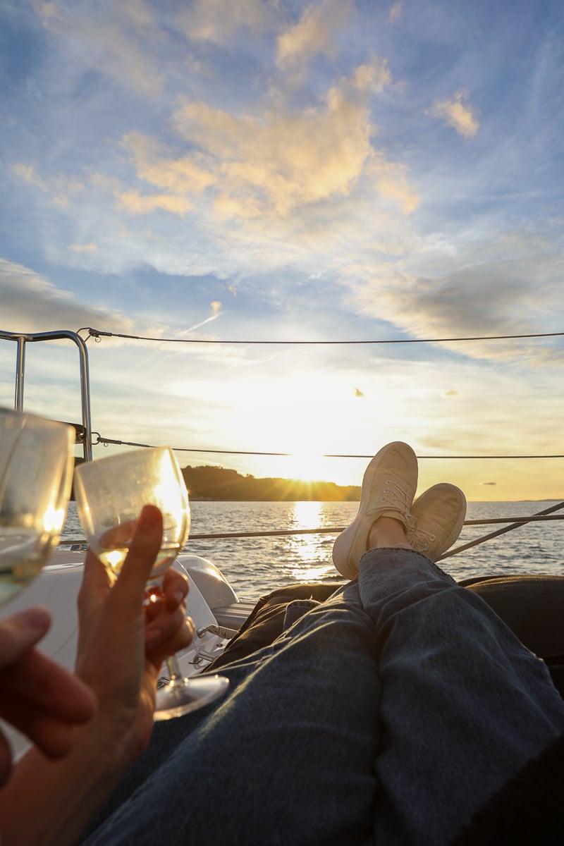 Holding a glass of wine with our feet up while watching the sunset from the sailboat