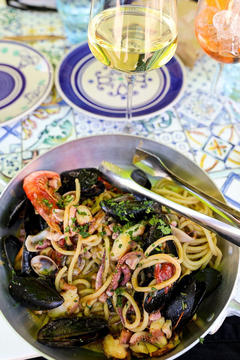 A plate of fresh pasta with seafood on top of a tile table, on the island of Capri