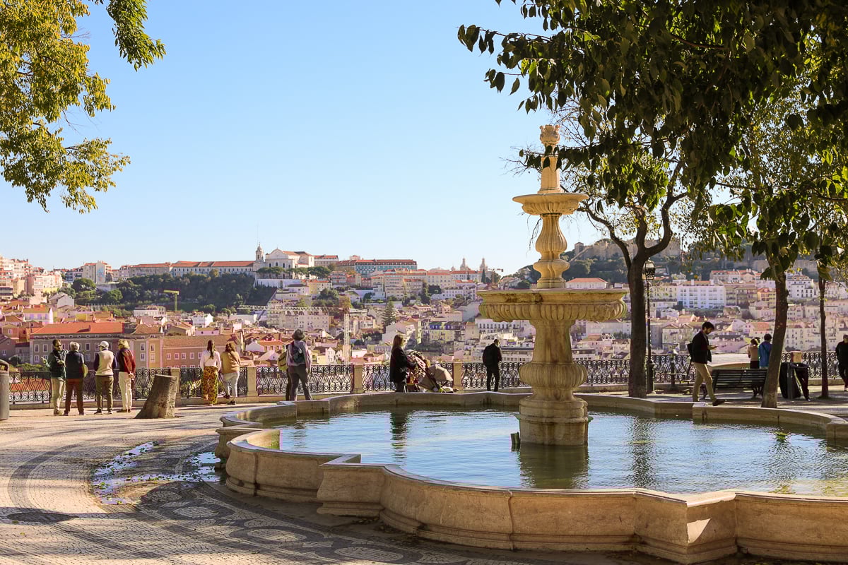 Beautiful fountain and groups of people enjoying the view at the Miradouro de São Pedro de Alcântara