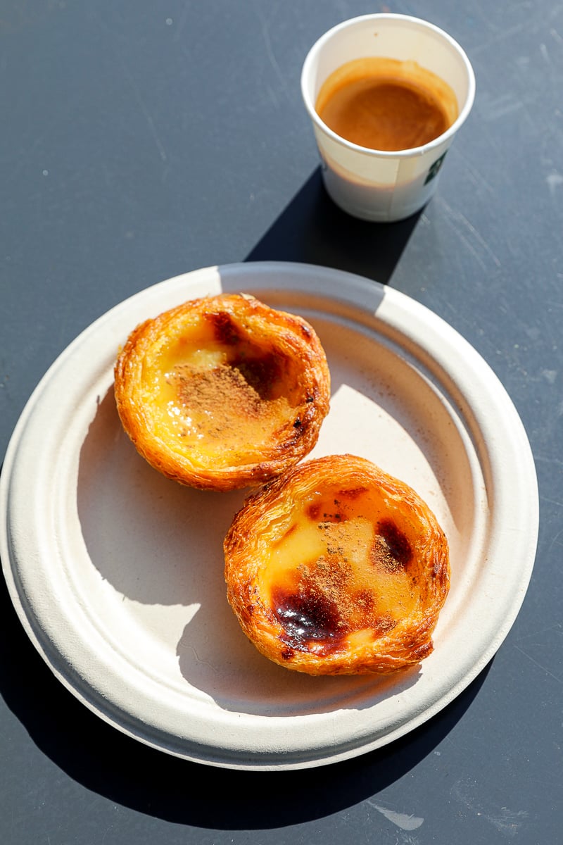Two pastel de natas on a plate and a cup of coffee