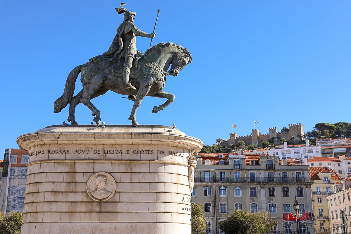 Statue of King John I at Praça da Figueira with a view of St. George's Castle atop a hill