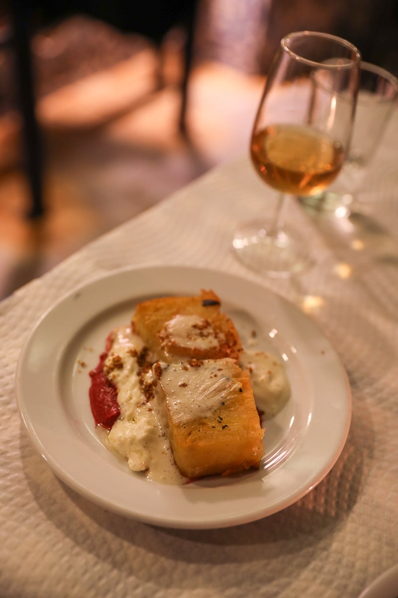 Plate of skate wing dish and a glass of wine at Tasca Pete