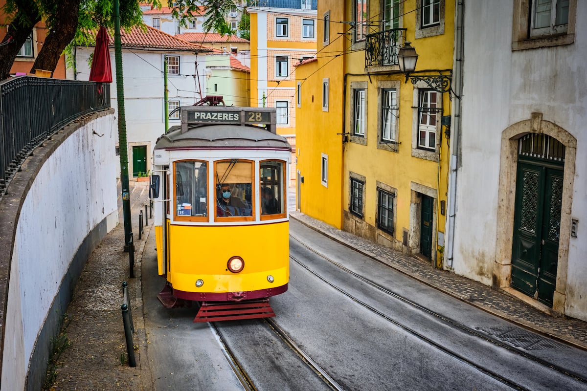 Yellow tram going up along a colorful neighborhood in Lisbon