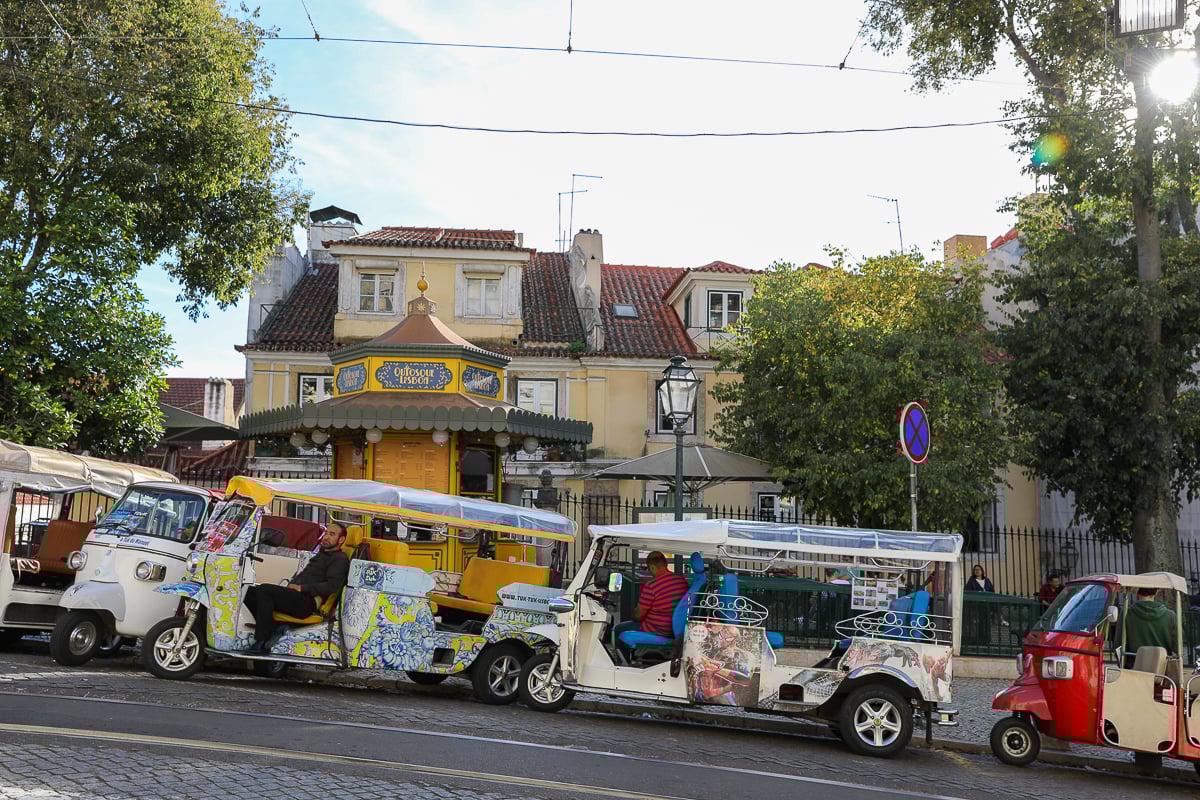 Colorful tuk-tuks going up an uphill road in Lisbon
