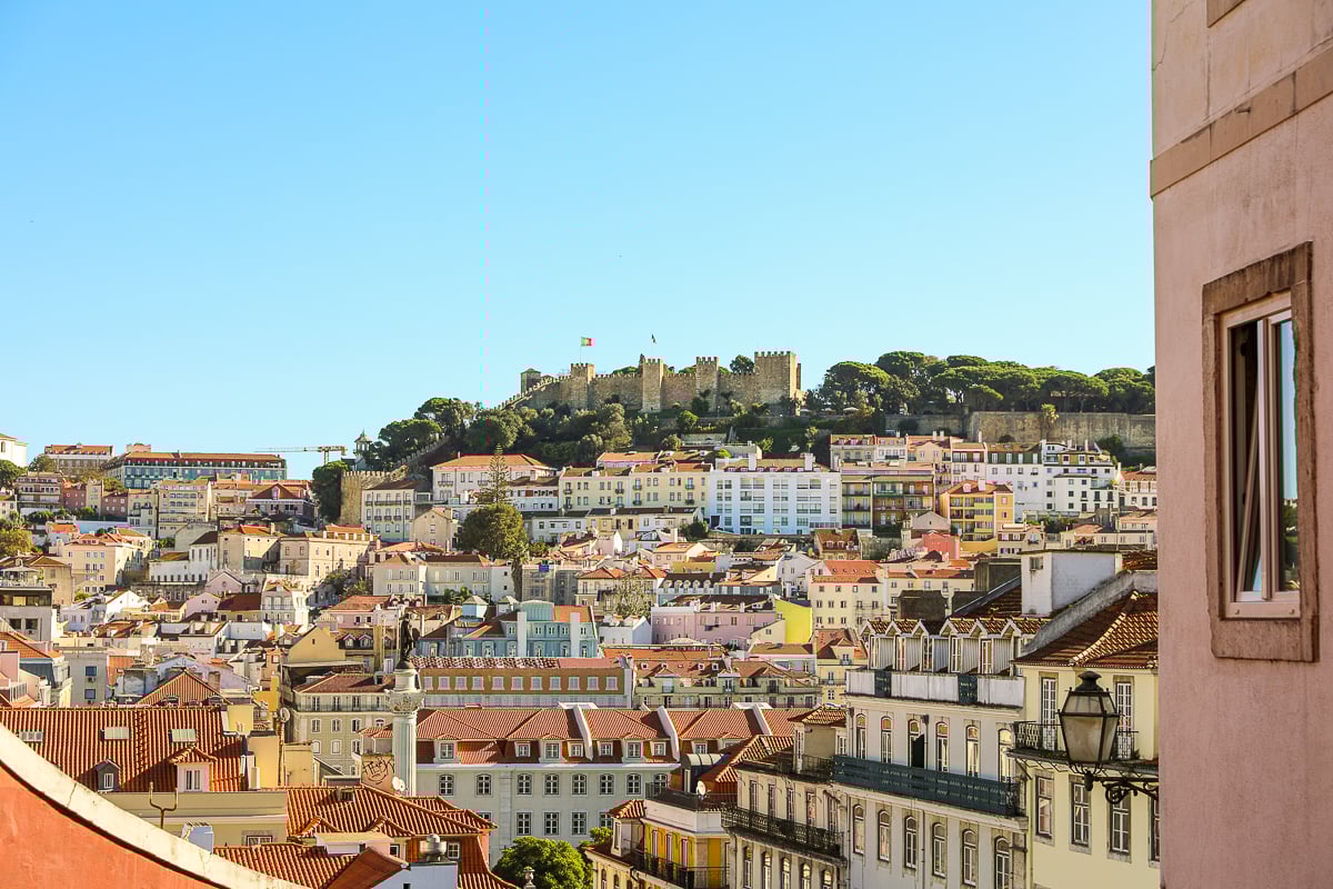 Colorful buildings of Lisbon on a sunny day with a view of a castle atop a hill