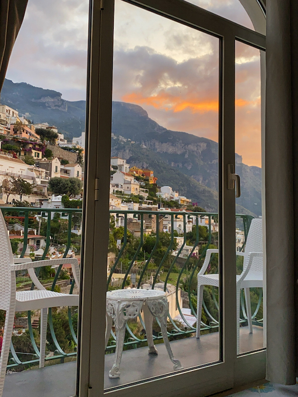Beautiful sunset view of the Amalfi Coast from inside of a hotel room, looking out of the balcony window