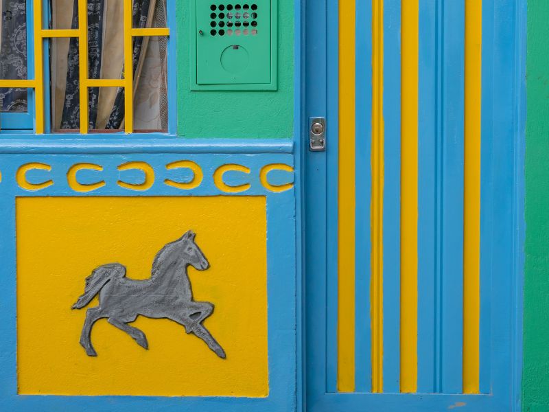 Gray horse and yellow horseshoes painted on a building's exterior