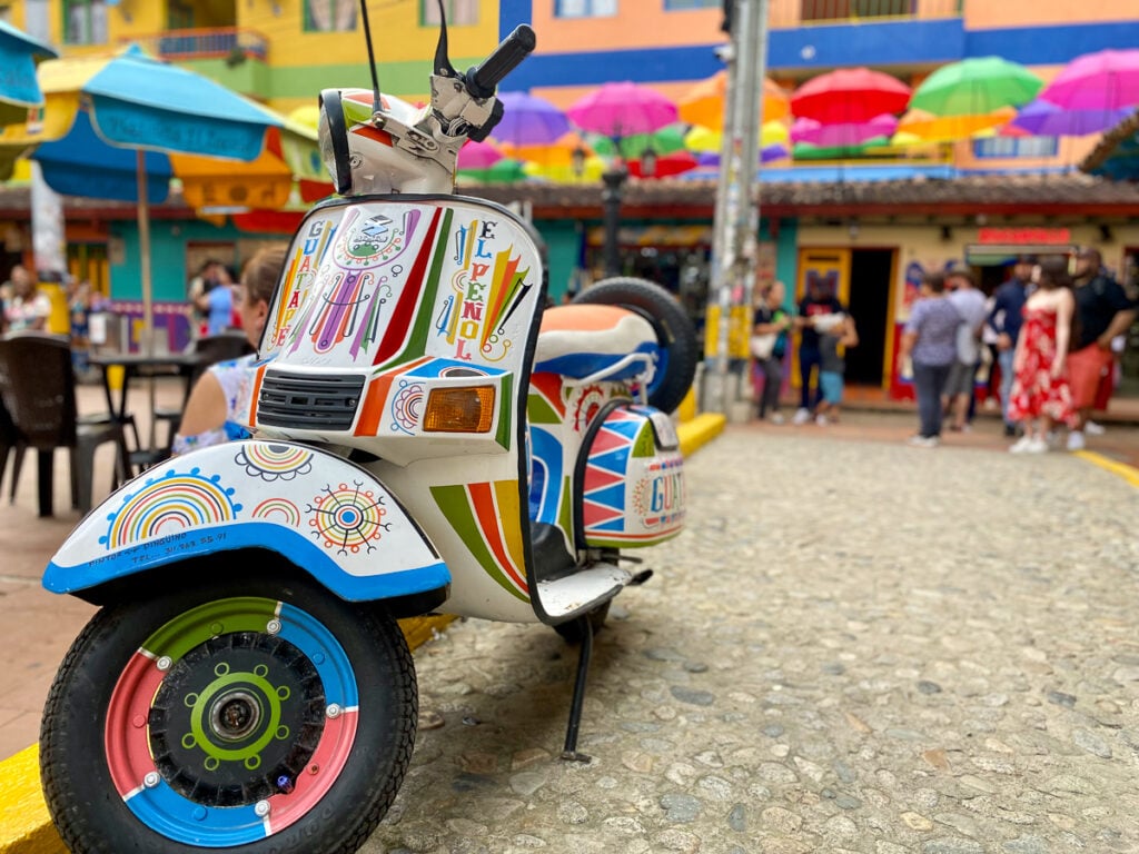 Colorful, painted scooter at the umbrella street. Walking under the colorful umbrellas is one of the amazing things to do in Guatape, Colombia.