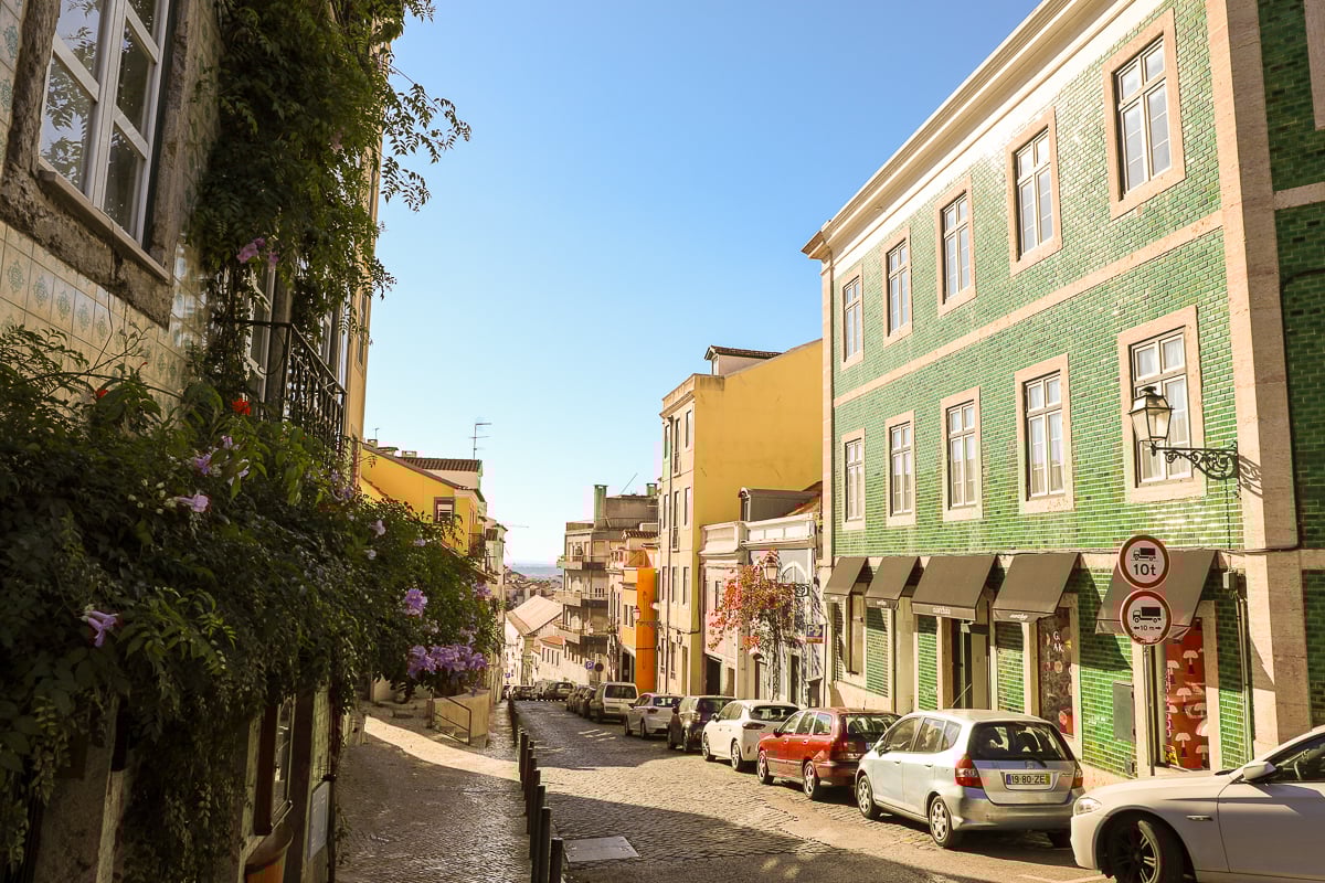 Colorful, quiet street lined with cars on a sunny day in Lisbon
